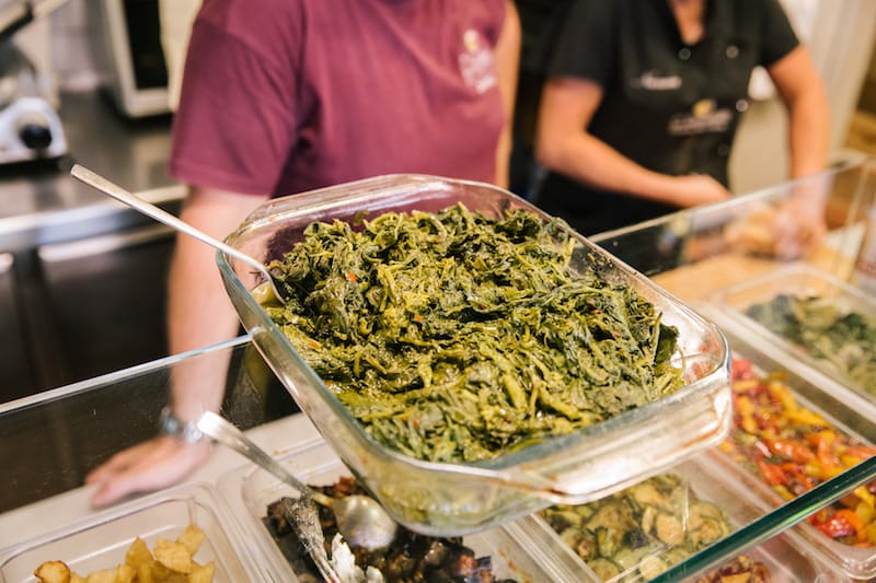 NAPLES, ITALY - 11 JUNE 2019: Friarelli (fried Neapolitan broccolis) are seen here together with other Neapolitan side dishes used to fill the cuzzetiellos, here at O' Cuzzetiello, a panini take away in Naples, Italy, on June 11th 2019.<br /> The cuzzetiello (bread bowl) is among the oldest and most traditional snacks in the city of Naples. It is made out of the “cozzetto” (the extremities of the bread), emptied of the crumb and filled with a traditional Neapolitan side contour : ragù sauce, fried meatballs, eggplant parmigiana, sausage and friarelli, etc.<br /> “O’ Cuzzetiello” is a Cuzzetiello panic take-away founded by Dario Troise in 2016, who succeeded in creating a project that he had been caressing for at least 15 years: a panini bar that serves only sandwiches in the shape of the cuzzetiello.