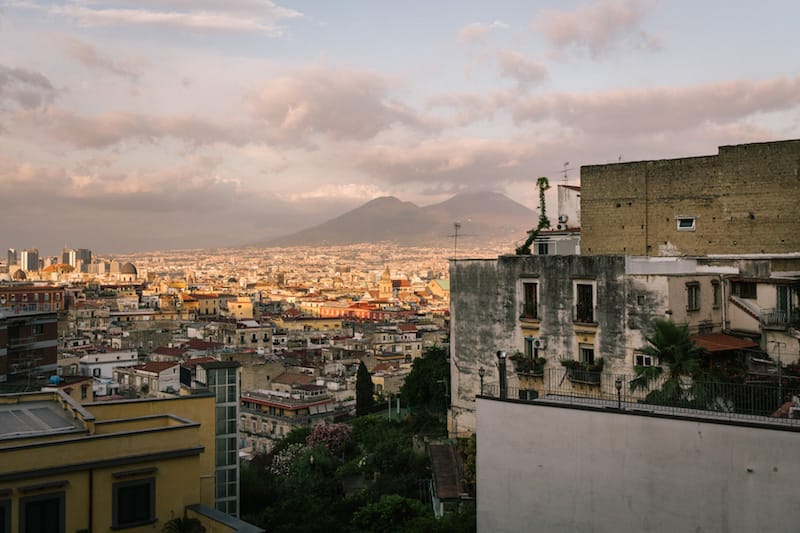 NAPLES, ITALY - 13 JULY 2019: A view of Mount Vesuvius is seen here from the terrace of the Osteria Totò Eduardo e Pasta e Fagioli, a restaurant in Naples, Italy, on July 13th 2019.<br /> The name of the Osteria is dedicated to the two masters of Neapolitan theatre and cinema: Totò (Antonio de Curtis) and Eduardo de Filippo. The idea came from Mario Bianchini, an aficionado of Neapolitan culture who wanted to pay tribute to his wife Rosaria de Curtis, a distant relative of Totò, the most famous actor in the history of Naples.<br /> The osteria was founded in the 1970s by Mario Bianchini who wanted to base its menu on traditional Neapolitan dishes. Mr Bianchini learned the art of cooking from his mother Anna.
