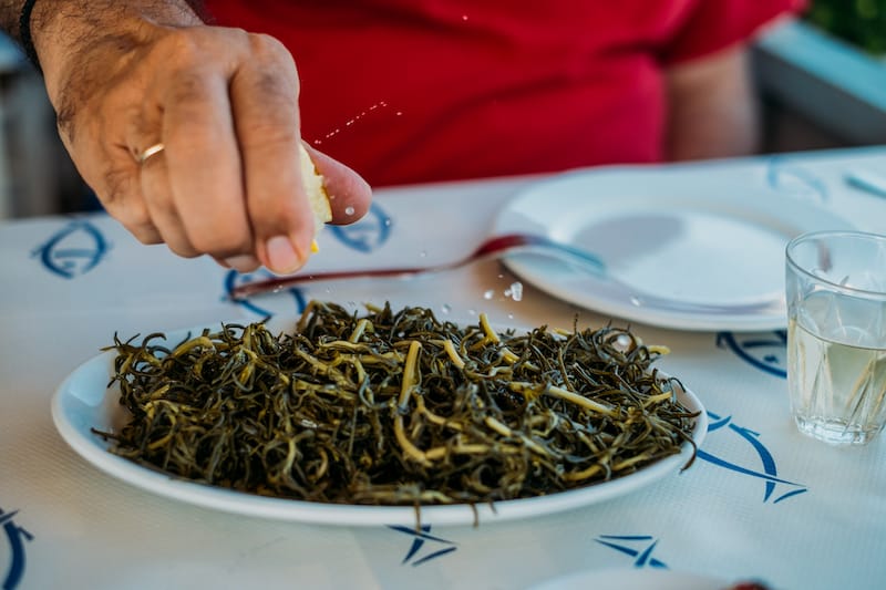 Cooked almira, a type of horta, are doused with lemon at Taverna tou Veletakou, photo by Manteau Stam restaurant lavrion
