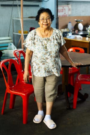A Thai woman stands in front of red chairs