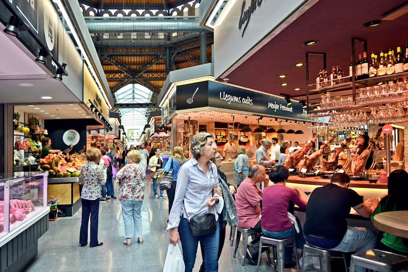 Customers stroll through the market as people eat at Escofet Oliver, photo by Paula Mourenza