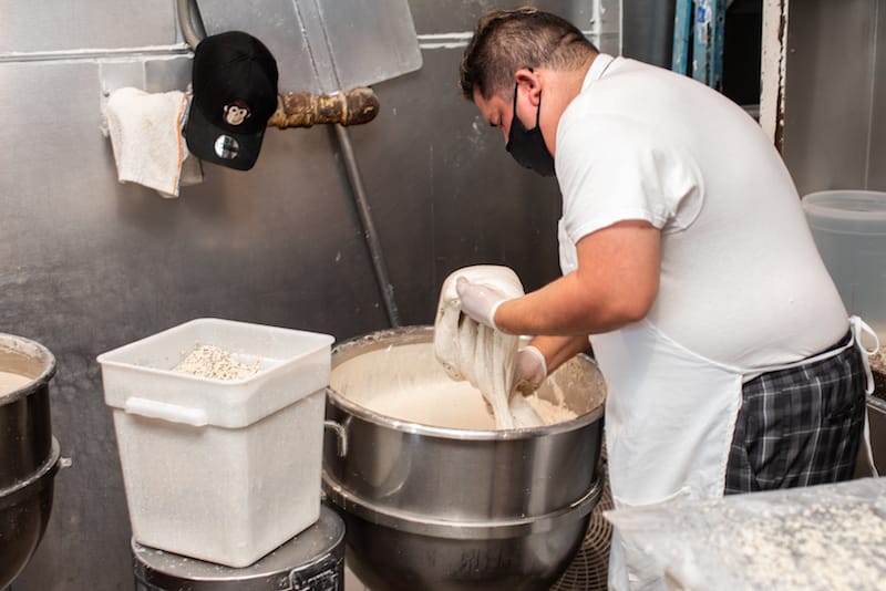 Jesus Osorio plunges his hands into a steel cauldron of wet dough, photo by Vitaly Belousov