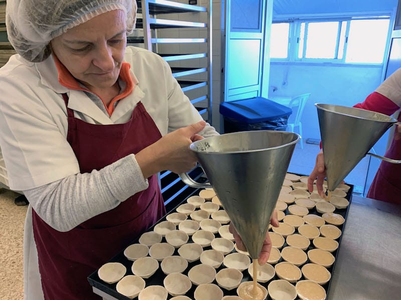 Two women at Sapa fill the pastry cups using a funnel and their fingers to control the liquid, photo by Célia Pedroso