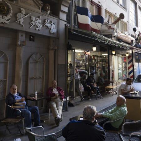 A group of older men hang around outside a block of eateries, photo by Julien Lasseur