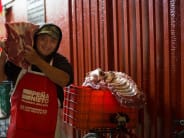 A butcher's assistant shuttles beef carcasses from the cooler to the butcher's table.