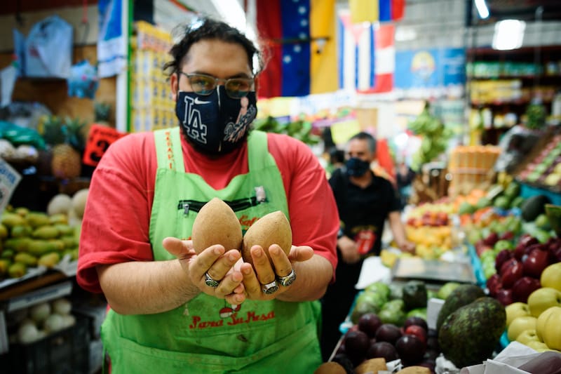 A vendor holds chicozapote at Mexico City’s Mercado Medellin, photo by PJ Rountree