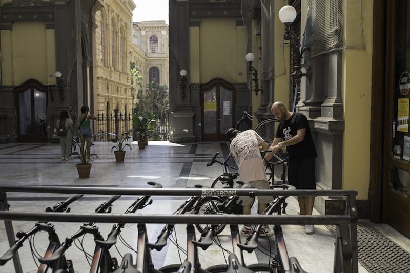 Bicycle House founder and manager Massimo Minopoli helps a cyclist outside the café, photo by Claudio Menna