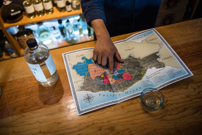Felix Monterroza displays a map of the 16 mezcal producing regions in Oaxaca at Cuish, his mezcaleria, photo by Jalil Olmedo