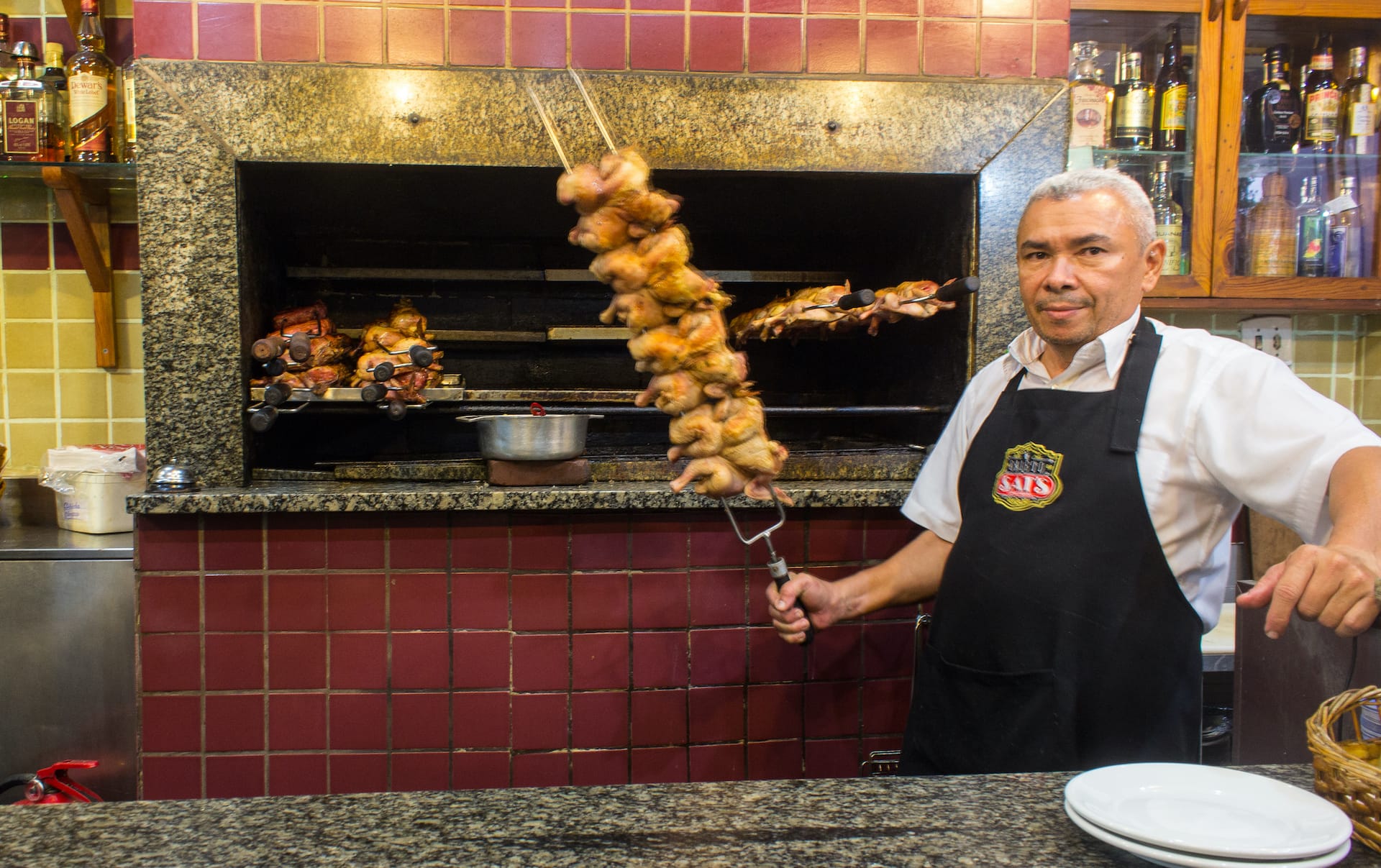 man holds a skewer of chicken at galeto sat's in rio