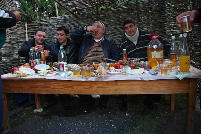 Men toast with glasses of wine at a Georgian supra, photo by Uta Bayer toast georgia