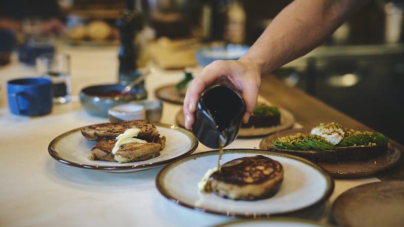 A smear of butter and generous pour of maple syrup on banana pancakes, photo by Alex Fisher
